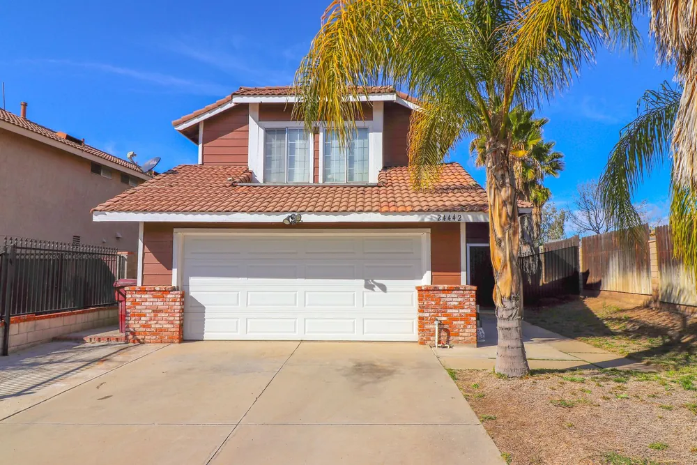 Stucco house with a white garage door and a palm tree